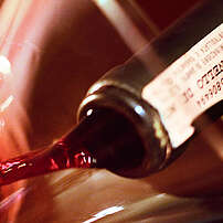 Brunello-Rotwein mit DOCG-Banderole am Flaschenhals wird in eine Karaffe geschenkt, Montalcino, Toskana, Italien