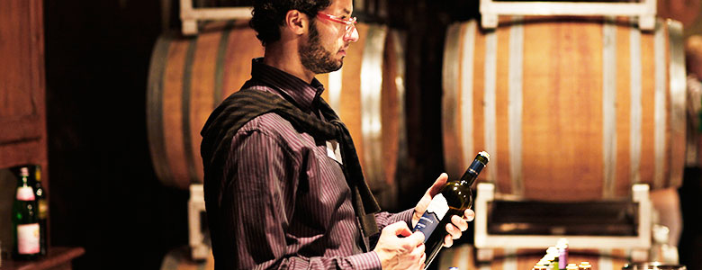 Italien, Valpolicella, Rotwein, Mann vor Weinfässern mit Weinflasche in der Hand,